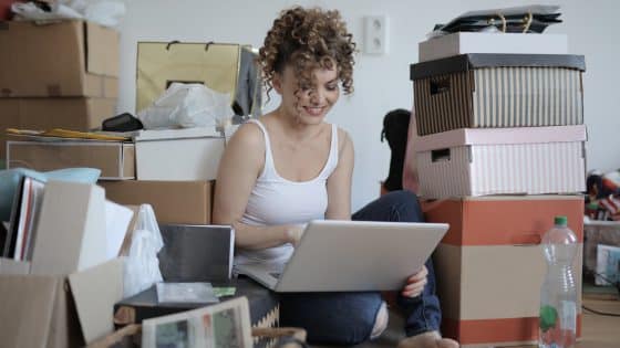 female shopaholic with laptop shopping online in messy living room