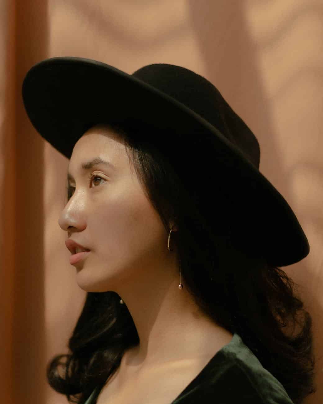 side view photo of woman in black fedora hat posing looking away