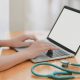 laptop near teal stethoscope in wooden table