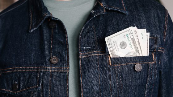 crop man with dollar banknotes in pocket of jacket