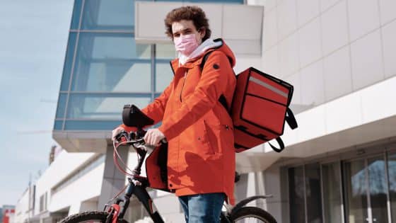 delivery man wearing a face mask and riding a bicycle