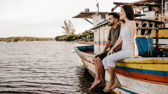 joyful couple sitting on old boat and holding hands